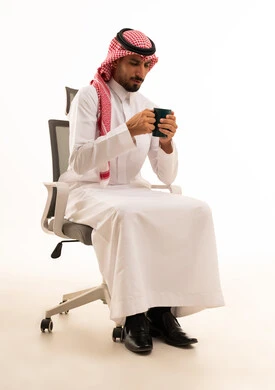 Saudi Man in Traditional Thobe Holding Mug on Office Chair