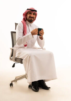 رجل أعمال سعودي يجلس على كرسي مكتب مع كوب