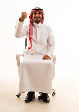 رجل سعودي بالزي التقليدي يرفع قبضة يده تعبيراً عن النجاح