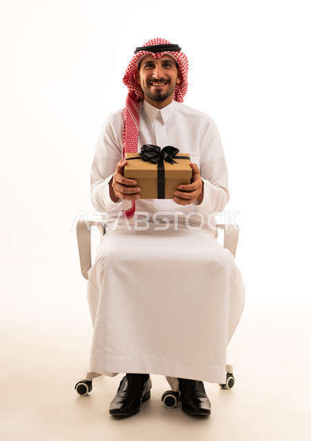 Smiling Saudi Man Holding Gift Box on White Background