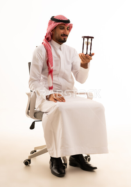 رجل أعمال سعودي يحمل ساعة رملية بخلفية بيضاء
