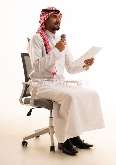 رجل سعودي يمسك بميكروفون على كرسي مكتب