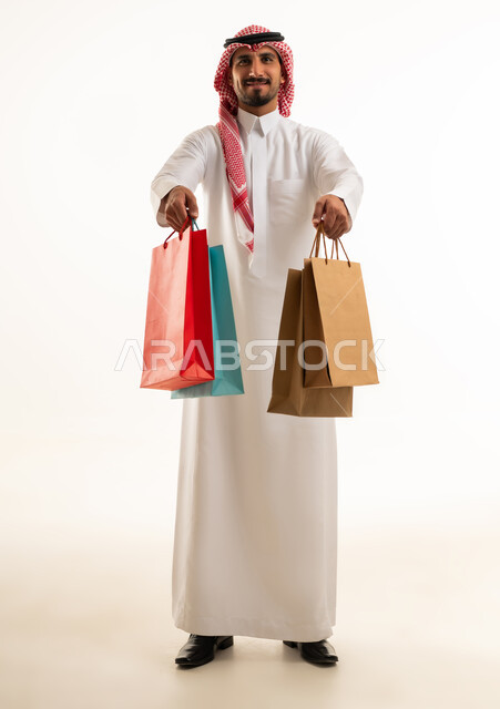 رجل سعودي بالزي التقليدي يحمل أكياس تسوق
