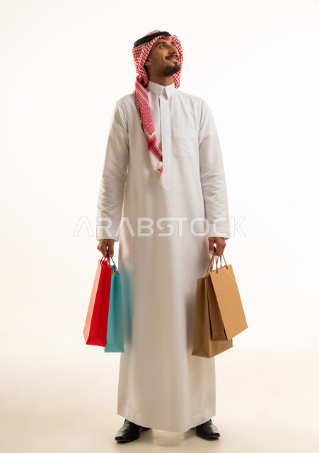 رجل سعودي يحمل حقائب تسوق على خلفية بيضاء