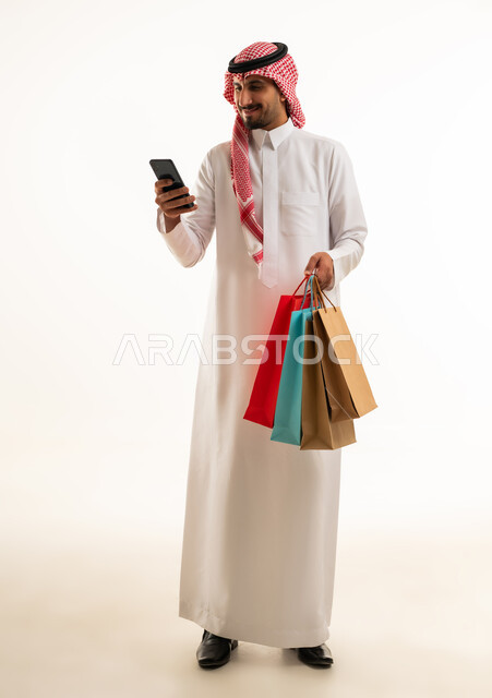 Saudi Man with Shopping Bags Using Smartphone