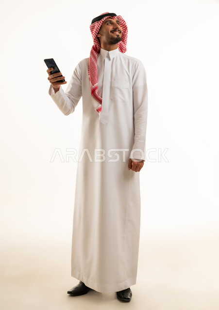 رجل سعودي بالزي التقليدي يمسك هاتف ذكي