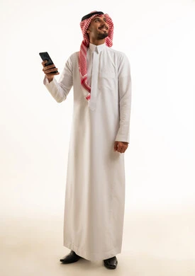 رجل سعودي بالزي التقليدي يمسك هاتف ذكي