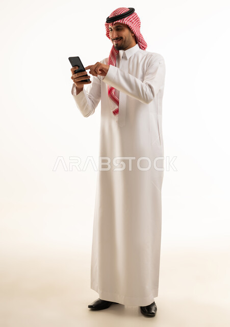 Saudi Man in Traditional Thobe Using Smartphone