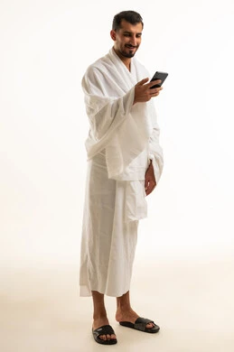 Saudi Pilgrim in Ihram Using Smartphone on White Background