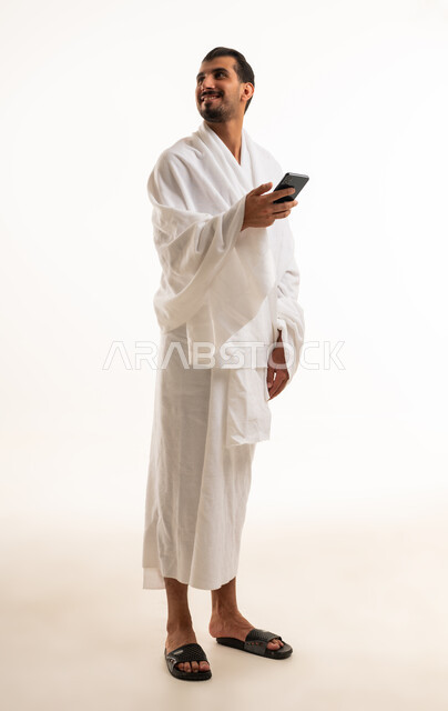 Saudi Man in Ihram Holding Smartphone on White Background