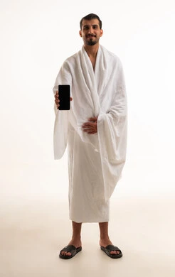 رجل سعودي بملابس الإحرام يحمل هاتفاً ذكياً