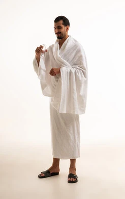 رجل عربي بملابس الإحرام يحمل زجاجة ماء في الاستوديو