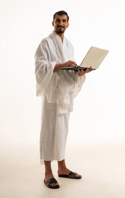 رجل سعودي بملابس الإحرام يستخدم لابتوب خلفية بيضاء