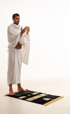 Saudi Man in White Ihram Praying on Mat in Studio