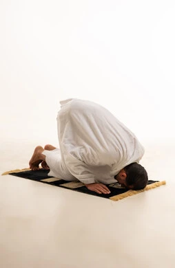 رجل مسلم ساجد أثناء الصلاة بخلفية بيضاء