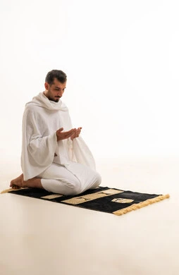 رجل سعودي بملابس الإحرام يدعو على خلفية بيضاء