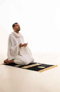 رجل سعودي بملابس الإحرام يدعو على سجادة الصلاة