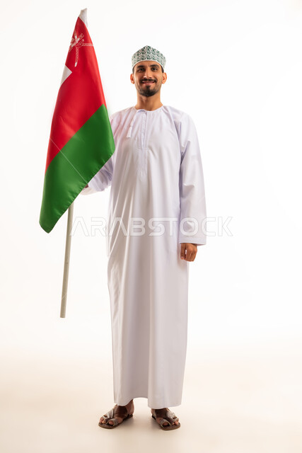 رجل عماني باللباس التقليدي يحمل علم سلطنة عمان
