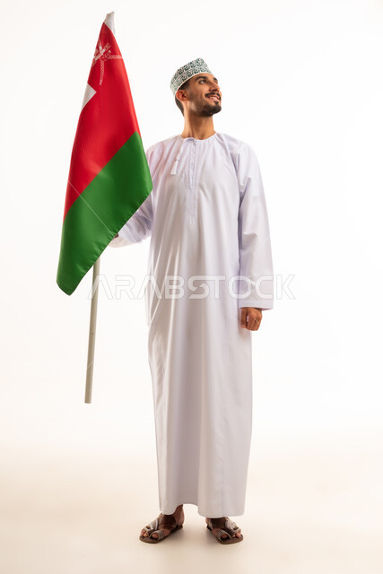 رجل عماني بالزي التقليدي يحمل علم سلطنة عمان