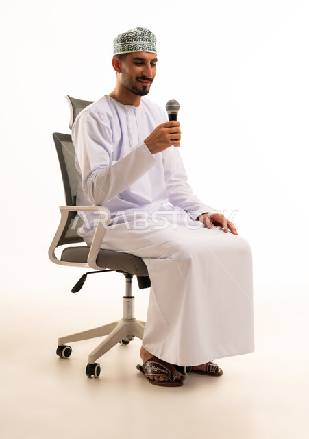 رجل عماني بالزي التقليدي يمسك ميكروفون