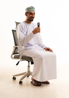 رجل عماني بالزي التقليدي يمسك ميكروفون