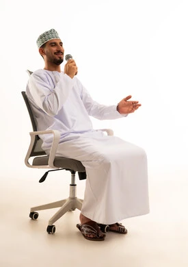 رجل عُماني يتحدث بالميكروفون بالزي التقليدي