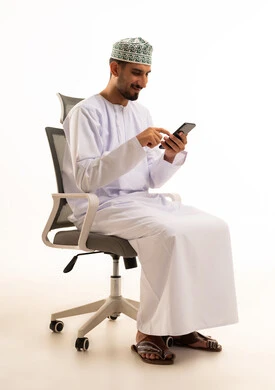 رجل عماني بالزي التقليدي يستخدم الهاتف الذكي