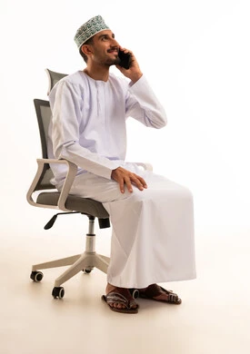 رجل عماني بالزي التقليدي يتحدث بالهاتف الذكي