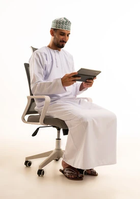 Omani Man in Traditional Dress Using Tablet in Office Chair
