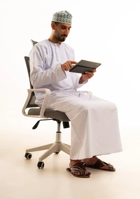 رجل عماني يستخدم جهاز لوحي على خلفية بيضاء
