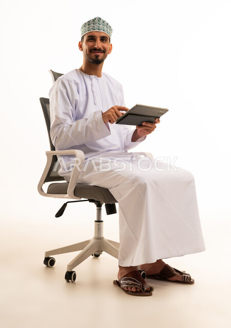 رجل عُماني محترف يستخدم جهاز لوحي في المكتب