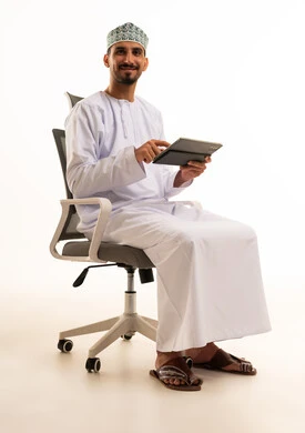 رجل عُماني محترف يستخدم جهاز لوحي في المكتب