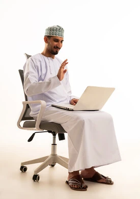 رجل عماني بالزي التقليدي يحيي عبر اللابتوب