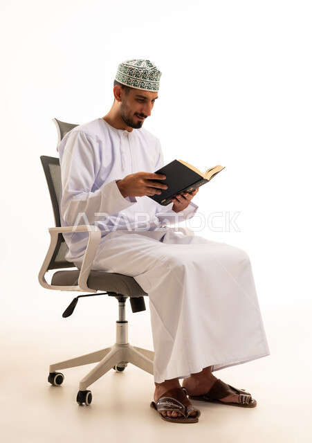 Omani Man in Traditional Dress Reading a Book