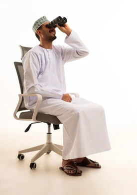 رجل عُماني بالزي التقليدي يستخدم المنظار