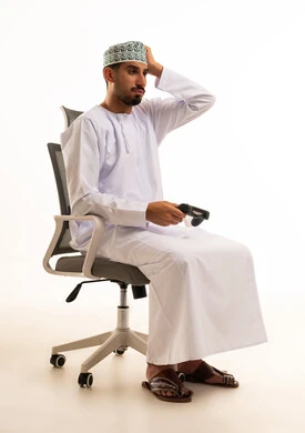 رجل عُماني مع جهاز تحكم ألعاب على خلفية بيضاء