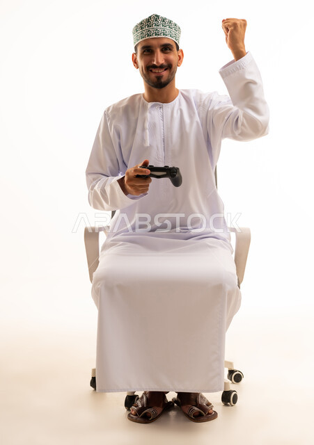 رجل عُماني يحمل جهاز تحكم ألعاب ويحتفل بالفوز