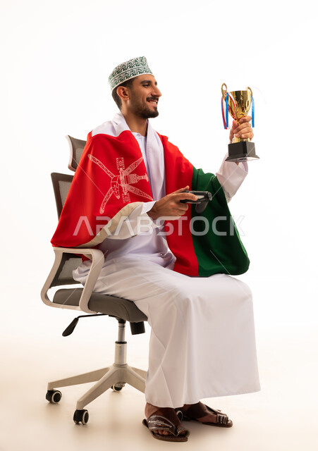 رجل عماني يحمل كأس الفوز بالألعاب الإلكترونية