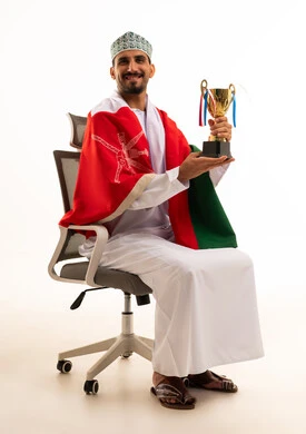رجل عُماني يحمل كأساً ذهبياً وعلم سلطنة عُمان