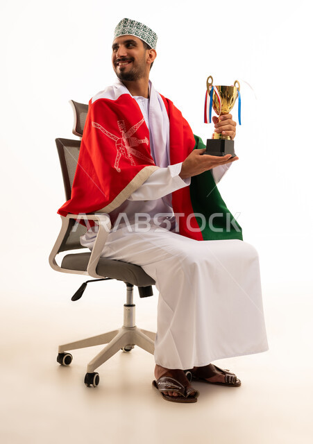Omani Man with Trophy and Flag in Office Chair