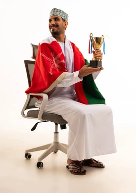 رجل عماني مع كأس وعلم على كرسي مكتب رجل عماني مع كأس وعلم على كرسي مكتب