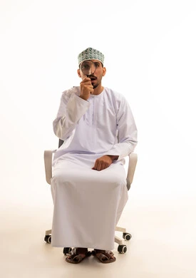 رجل عماني يحمل عدسة مكبرة على خلفية بيضاء