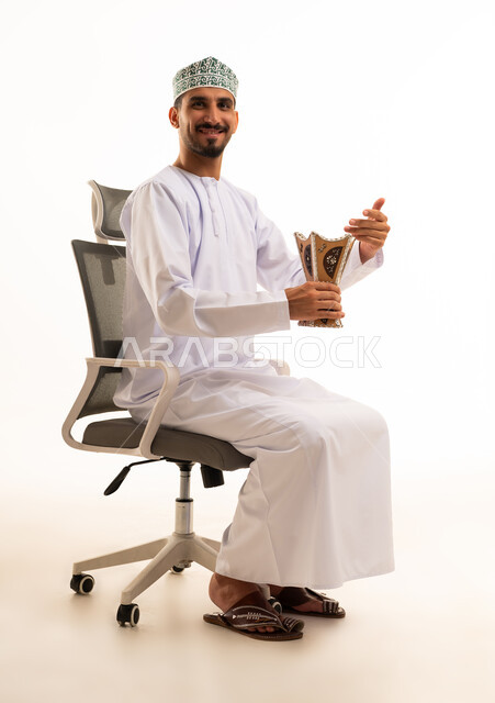 رجل عماني بالزي التقليدي يحمل مبخرة خشبية