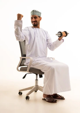رجل عُماني يرفع الأثقال على كرسي المكتب