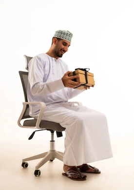 رجل عُماني بالزي التقليدي يحمل صندوق هدايا