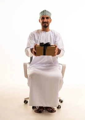 رجل عُماني يحمل صندوق هدايا في استوديو أبيض