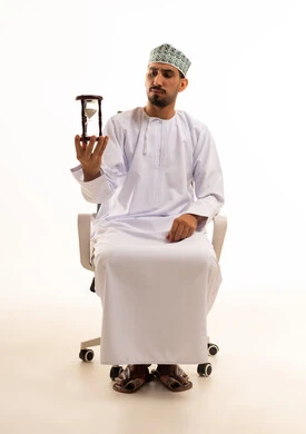 Omani Man Holding Hourglass in Office Chair White Background