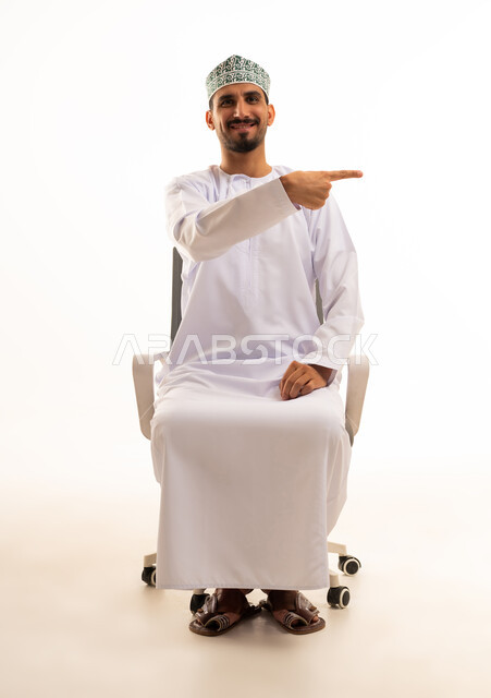 رجل عماني بالزي التقليدي يشير بيده على خلفية بيضاء