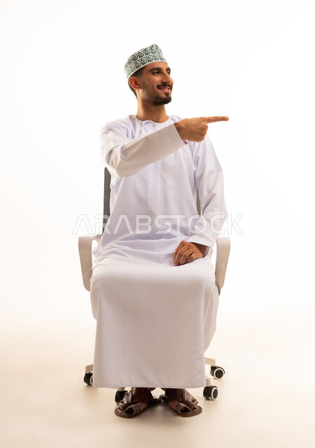 رجل عماني باللباس التقليدي يشير بيده على خلفية بيضاء