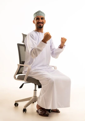 رجل عماني يحتفل بالنجاح على كرسي مكتب